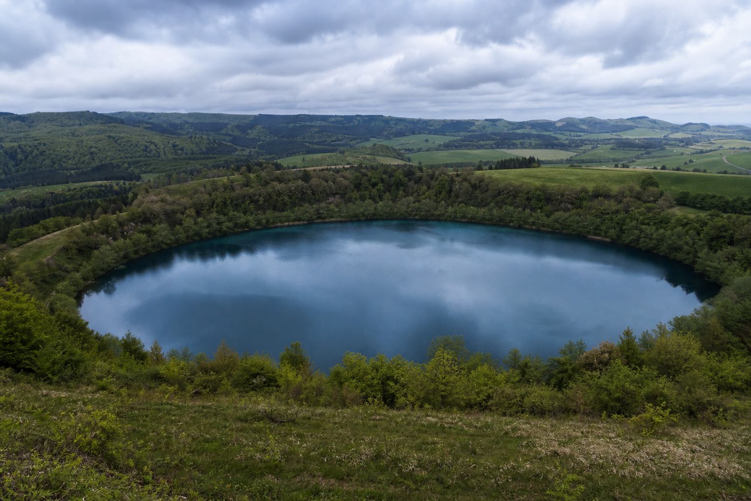 Runder Kratersee mit Waldsaum in der Vulkaneifel